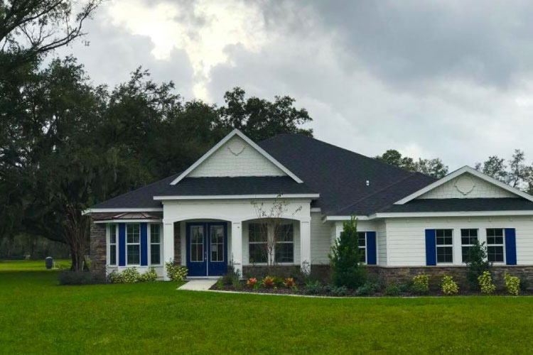 A new construction home in Plant City, Florida, featuring a large green lawn and plenty of trees in the backyard. 