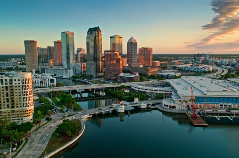 Aerial view of Downtown Tampa and the waterfront at sunset with the best Tampa suburbs visible in the distance