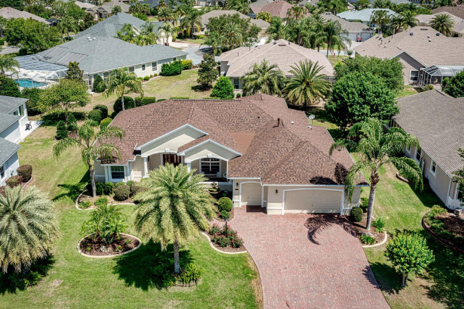 A large home surrounded by palm trees and neighboring houses in Bridgeport — one of The Villages neighborhoods in Florida.
