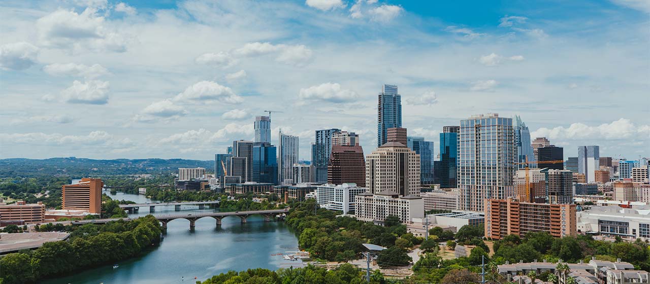 An aerial view of the Austin skyline. The Colorado river is in view as well as many large skyscrapers