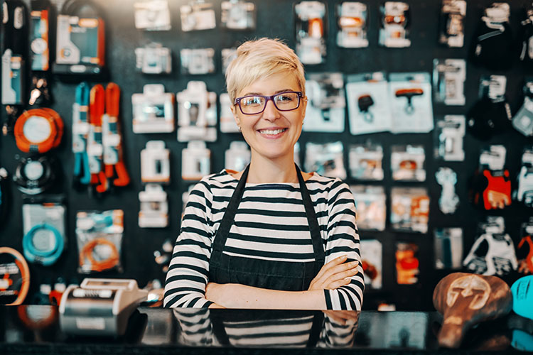 A smiling pop-up booth owner, selling hardware like wrenches, and safety equipment like heavy-duty gloves