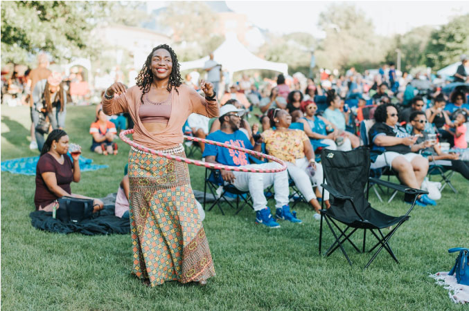 A woman is hula hooping on the lawn during a summer concert in Cleveland, Ohio.
