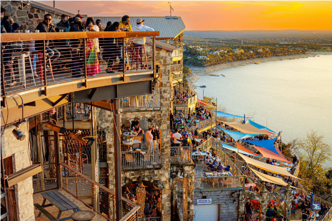 View of a bustling lakeside restaurant in Austin, Texas, during sunset