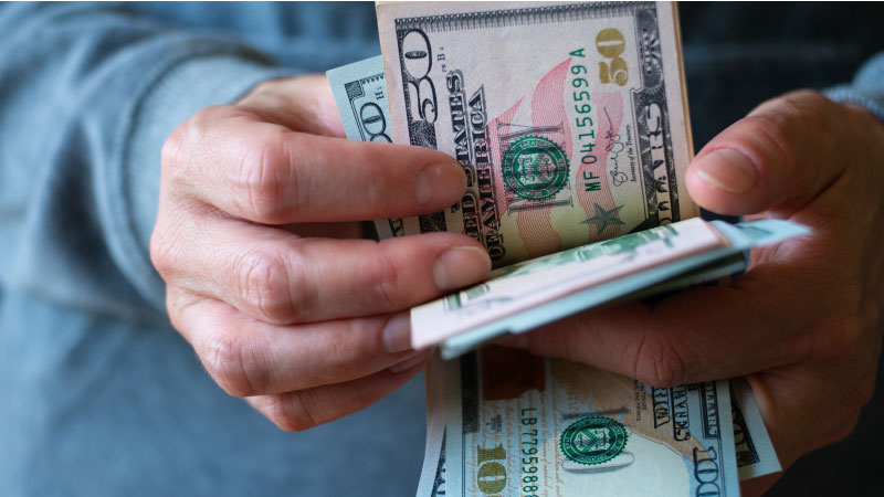 Close-up of a pair hands counting a series of large U.S. bills