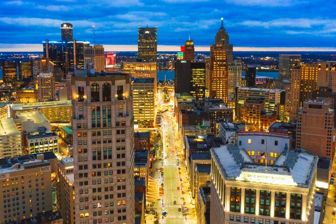 Aerial view of Downtown Detroit at night with the streets brightly illuminated by city lights and cars.