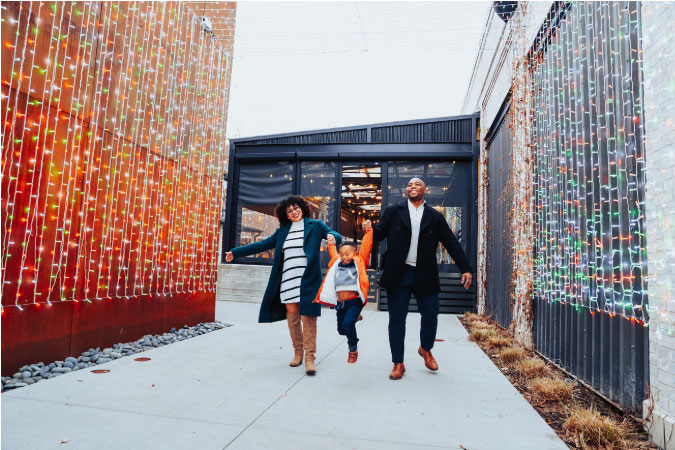 A happy family is walking together through an illuminated path in Columbus, Ohio, during the holiday season