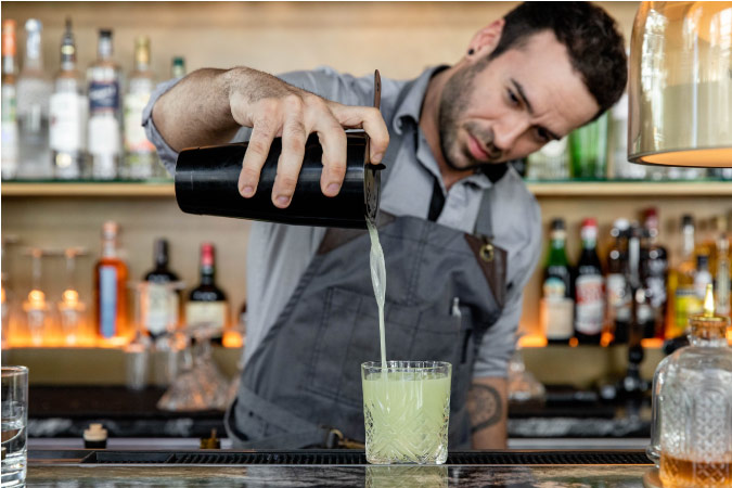 A mixologist pours a cocktail at The BEZEL Denver — a luxurious establishment located in the Sheraton Denver Downtown hotel lobby.
