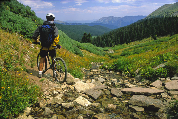 A mountain biker pauses during a ride to admire the beautiful summer view in Breckenridge, Colorado.