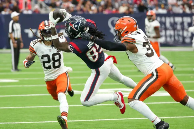 Houston Texans Wide Receiver Noah Brown in mid-air making a catch between two Cleveland Browns players. 