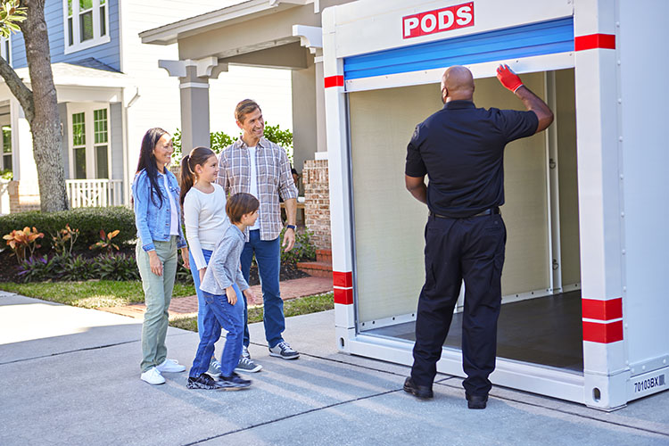 A family has their PODS container delivered to their driveway, where a driver walks them through how to best use it
