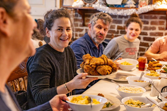 Happy diners are sharing a family-style Southern meal at Mrs. Wilkes’ Dining Room in Savannah, Georgia.