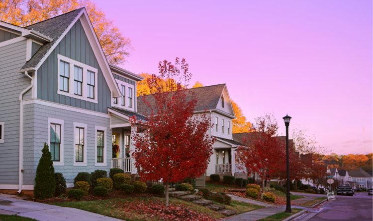View of a quiet Raleigh, North Carolina, neighborhood during an autumn sunset. The leaves on the trees have turned a deep red color and have started to fall to the ground.