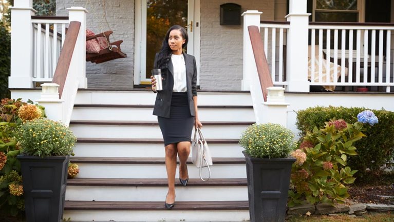 Business woman walking down porch stairs leaving home for work
