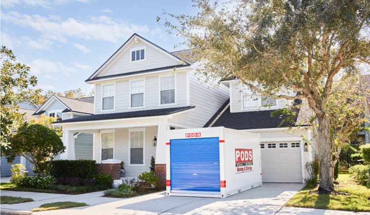 A PODS portable moving and storage container is positioned conveniently in the driveway of a two-story home in Tampa, Florida.