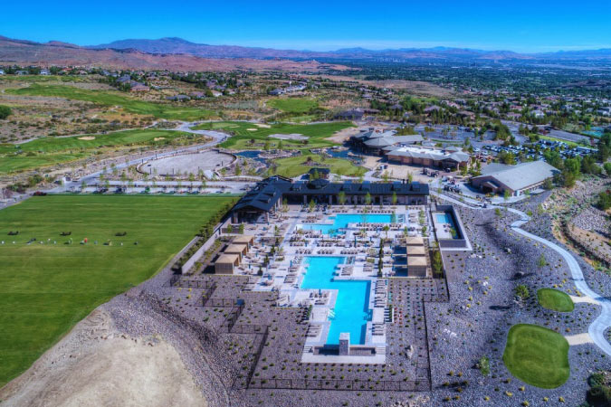 Aerial view of The Club at ArrowCreek in Reno’s ArrowCreek neighborhood, featuring two pools, expansive green lawns, and a distant mountain view.