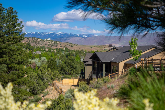 A beautiful single-family home in the Caughlin Ranch neighborhood of Reno, Nevada, surrounded by lush woodlands with a view of the mountains in the distance.