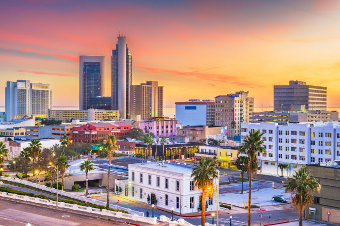 Sunset view of Downtown Corpus Christi, Texas, featuring city buildings in a variety of heights and colors.