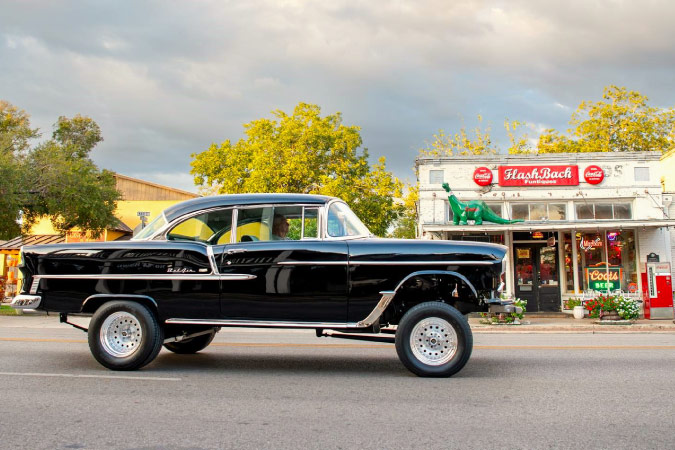 A vintage car enthusiast travels in his pride and joy past a retro soda shop in Boerne, Texas — one of the best cities near San Antonio.