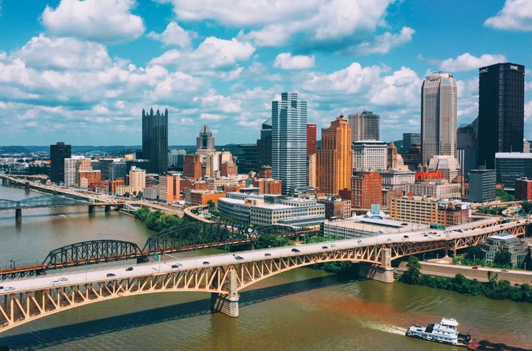 Daytime aerial view of Pittsburgh, Pennsylvania, with some of the Pittsburgh suburbs visible in the distance