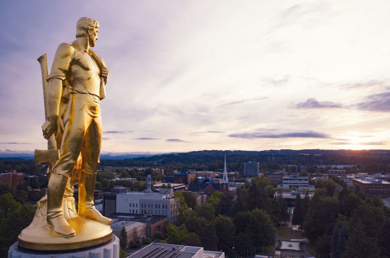 View of the “Oregon Pioneer” statue that sits atop the Oregon State Capitol, looking out over the city of Salem, Oregon.