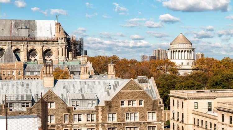 A rooftop view of the tops of buildings in the Morningside Heights neighborhood of New York City. It’s autumn, and Grant’s Tomb is seen in the background amidst copper-colored leaves.
