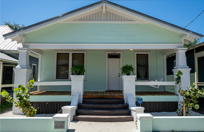 A white and light-green bungalow in Ybor City with a large covered porch.