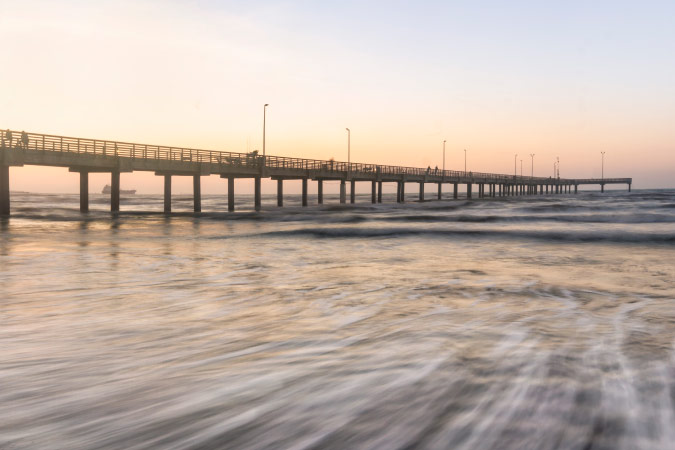 A surreal, long-exposure view of water flowing under the Horace Caldwell Pier and onto the beach of Mustang Island in Corpus Christi.
