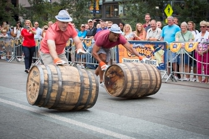Local Cincinnati men compete in a barrel rolling contest during Oktoberfest Zinzinnati as hundreds of onlookers watch from the sidelines.