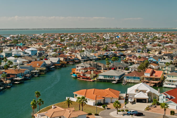 Aerial view of waterfront homes in North Padre Island — one of the best Corpus Christi neighborhoods — seen on a sunny day.
