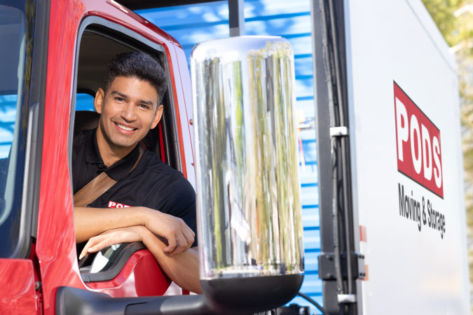 A smiling PODS driver is leaning out of the driver side window of his truck as he prepares to transport a PODS portable moving container to one of the best neighborhoods in Reno, Nevada.
