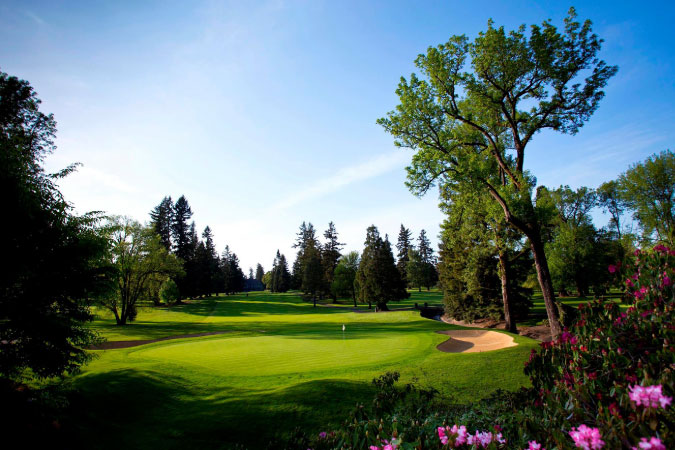 Golf course at the Portland Golf Club, featuring vibrant green grass with lush trees and pink flowers around the edges, in Raleigh Hills — one of the best Portland suburbs.