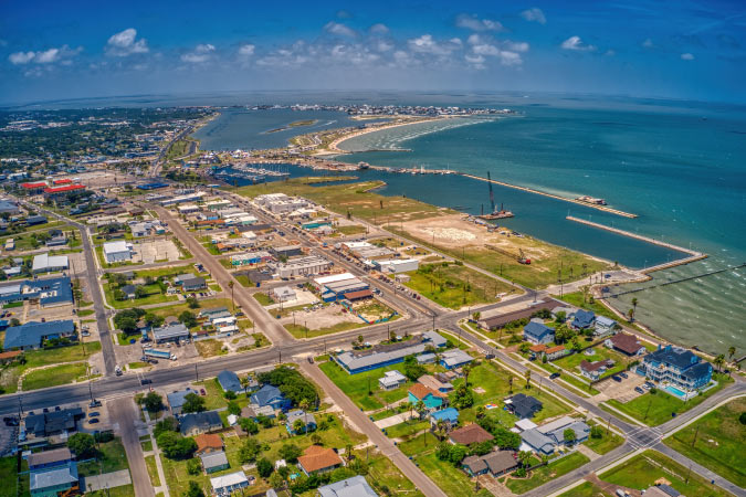 Aerial view of Rockport, Texas, on a sunny summer day, featuring residential neighborhoods and expansive coastal waters.