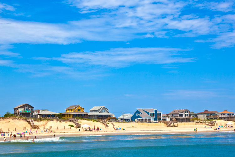 View of beachfront cottages built atop sand dunes in Nags Head, North Carolina, as seen from the water.