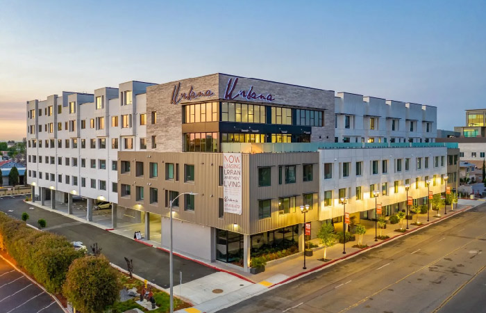 Exterior view of the Urbana apartment building in Chula Vista, California. The building has a modern block design with an urban flair. The first floor features open-air parking. 