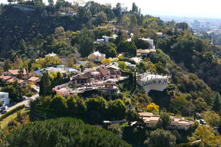 Aerial view of luxury mansions in Beverly Hills, California. The large estates intermingle with lush trees and vegetation for a natural escape from the concrete jungle of Los Angeles.