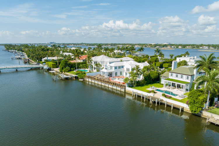 Aerial view of a row of luxury waterfront homes on Everglades Island in Palm Beach, Florida, on a beautiful summer day.