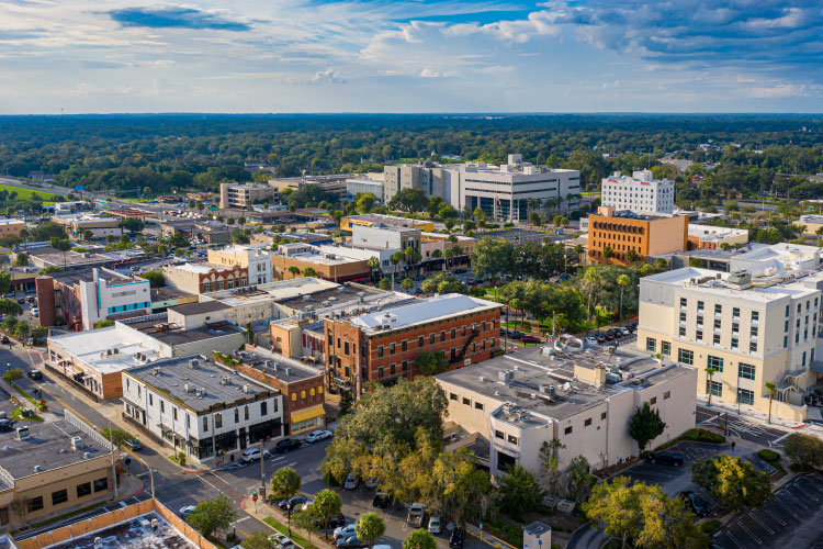 Aerial view of Downtown Ocala, Florida, in the summer. The buildings aren’t very tall, and there’s a great deal of wooded nature surrounding the city.