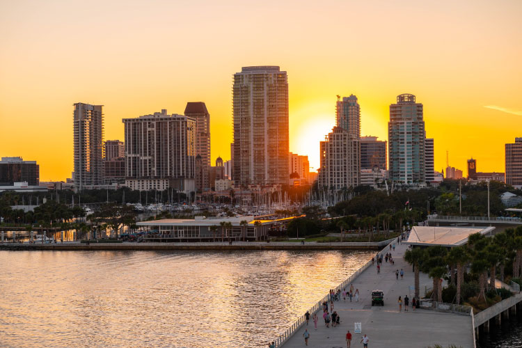 View of Downtown St. Petersburg, Florida, from the new pier during sunset. The water is sparkling as the sun beams between the tall city buildings.