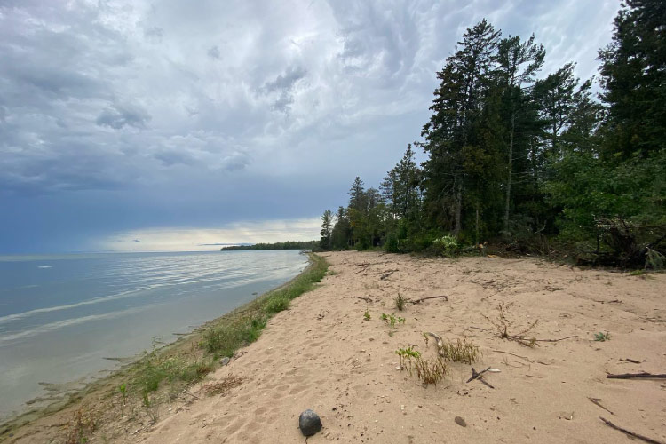 A peaceful view of Lake Michigan on a cloudy day, as seen from a sandy beach in Ford River Township, Michigan. 