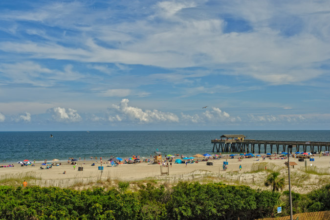 Tybee Island Beach and pier seen from behind the dunes on a sunny day.