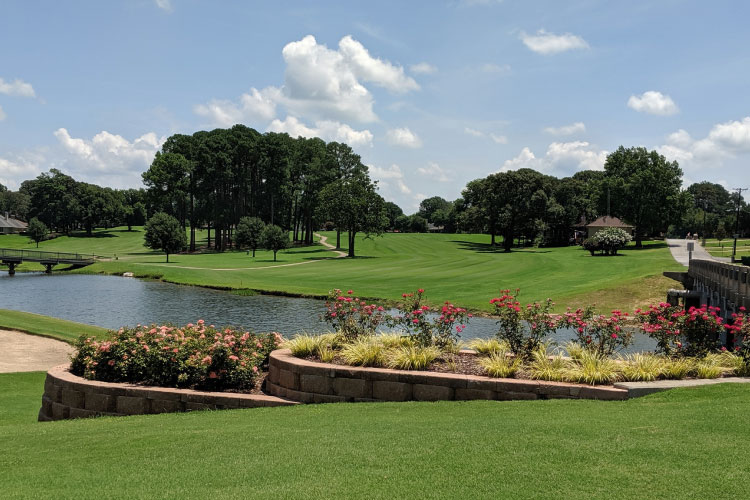 View of the golf course in the Emerald Bay community of Bullard, Texas. There’s a waterway running through the golf course and two small bridges crossing it. The grass is perfectly manicured, and there are small groves of trees throughout.