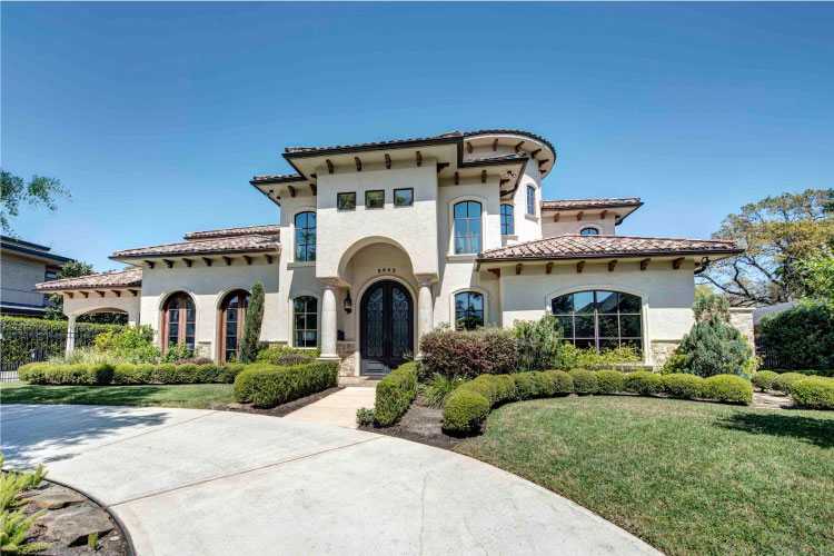 A large luxury home in Piney Point Village, Texas. The home features a Spanish villa look, with an adobe exterior and clay tile roof.