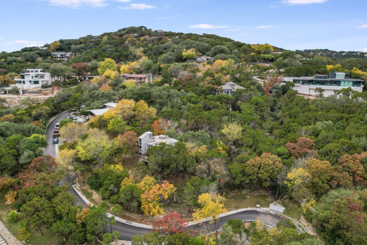 A neighborhood nestled among the trees in West Lake Hills, Texas. A winding road curves through the hilly residential area.