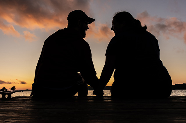 A silhouette of a retired couple holding hands on a dock built on Alabama’s Gulf Coast