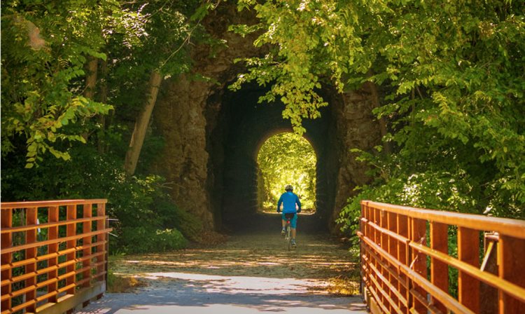 A cyclist in blue clothes rides their bicycle though the Katy Trail Rocheport Tunnel in Rocheport, Missouri.