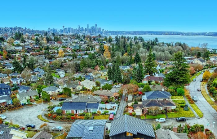 Aerial view of the waterfront neighborhood of Southeast Magnolia in Seattle, Washington, with the city skyline visible in the background.