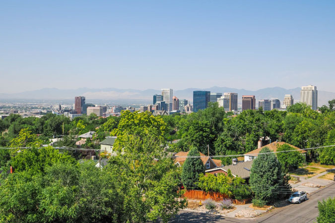 The Greater Avenues neighborhood in Salt Lake City, Utah, with a view of the mountains and city skyline beyond the treetops.