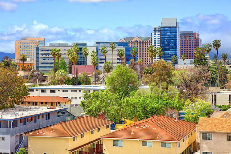 The skyline of downtown San Jose, California, during the day. There are colorful buildings and trees scattered throughout the image. 