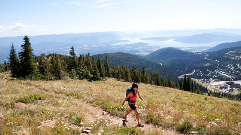 A woman is wearing a backpack while hiking up Mt. Schweitzer on a sunny day.