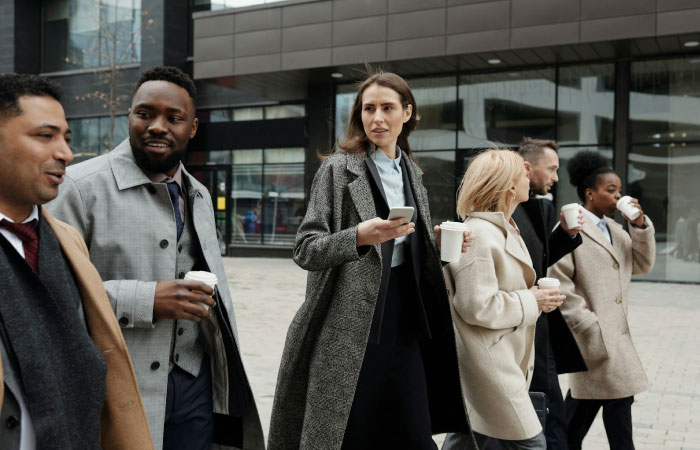 Several professionals walk together through the city while on a coffee break.